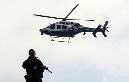 A police helicopter flies over a member of security forces near a courthouse in Mugla, western Turkey, on February 20, 2017