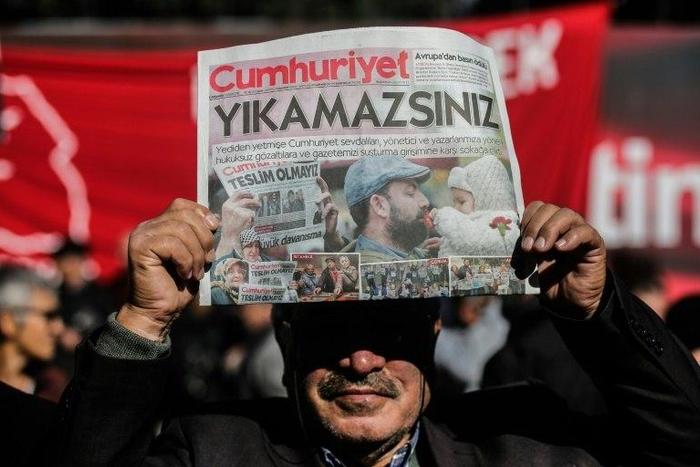 A protester holds a copy of the latest edition of the Turkish daily newspaper Cumhuriyet during a demonstration outside the newspaper's headquarters in Istanbul on November 2,2016