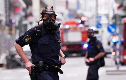 Police officers wearing gas masks on duty at the scene of a truck attack in central Stockholm on April 7, 2017