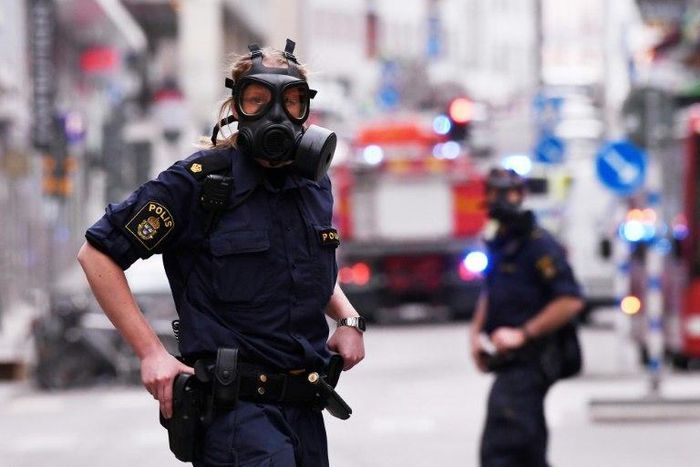 Police officers wearing gas masks on duty at the scene of a truck attack in central Stockholm on April 7, 2017