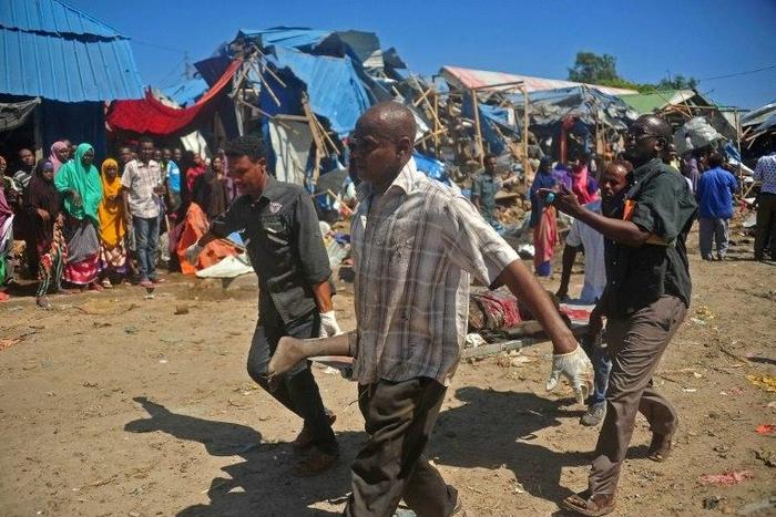 Soldiers assisted by some residents carry the body of a victim from the scene of a suicide car bomb attack at a market in Somalia's capital, Mogadishu on November 26, 2016