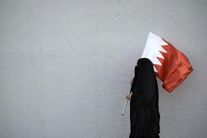 A woman holds the flag of Bahrain, a Shiite-majority Gulf kingdom