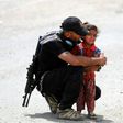 An Iraqi soldier helps a girl whose family has fled their home in the west of Mosul on May 26, 2017