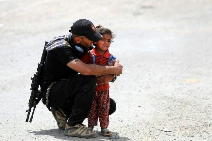 An Iraqi soldier helps a girl whose family has fled their home in the west of Mosul on May 26, 2017