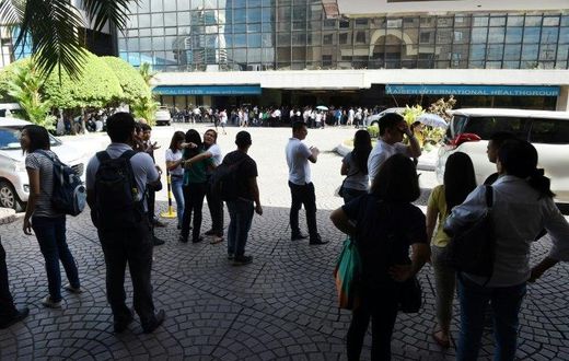 Office workers stand on the grounds of an office building in the financial district of Makati in Manila on April 8, 2017, after a 5.7 magnitude earthquake struck