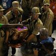 Firefighters assist a reveller of the Unidos da Tijuca samba school at the Sambadrome in Rio de Janeiro early on February 28, 2017, after the third floor of an allegorical car collapsed during the second night of Rio Carnival