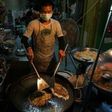 A man prepares food at a street stall in the Phrakanong district of Bangkok