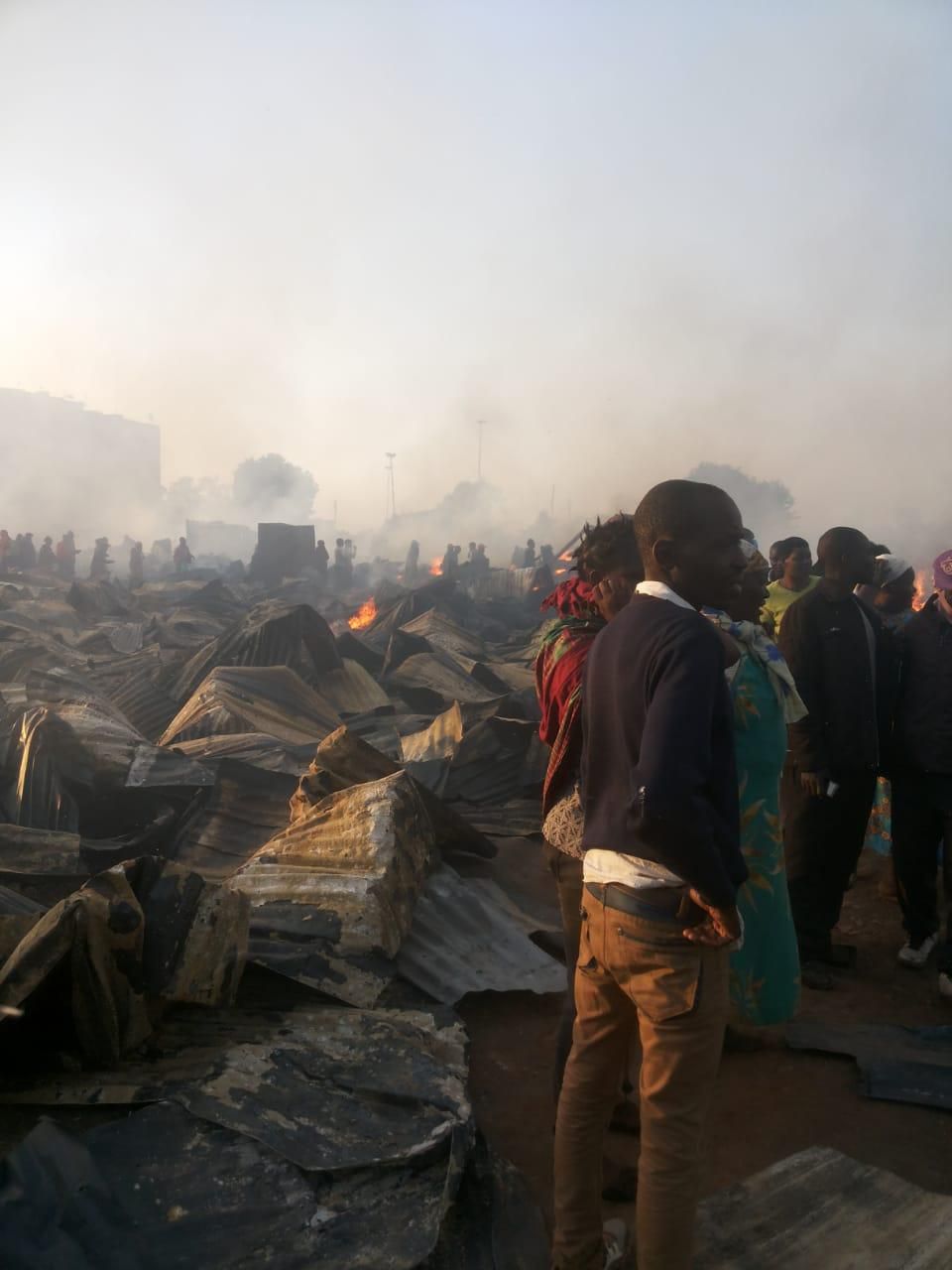 Locals look on as fire spreads at the Toi Market on Tuesday March 12, 2019 (Oliver Oketch)