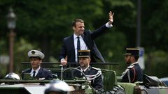 French President Emmanuel Macron (C) waves as he parades in a car on the Champs Elysees avenue after his formal inauguration ceremony on May 14, 2017 in Paris