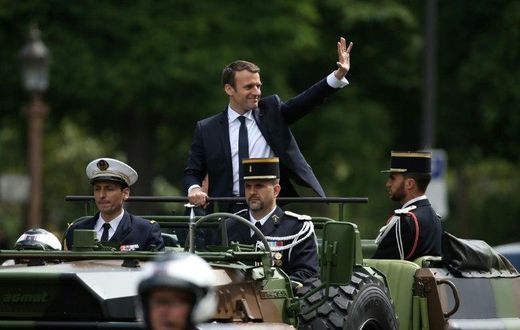 French President Emmanuel Macron (C) waves as he parades in a car on the Champs Elysees avenue after his formal inauguration ceremony on May 14, 2017 in Paris