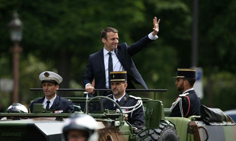French President Emmanuel Macron (C) waves as he parades in a car on the Champs Elysees avenue after his formal inauguration ceremony on May 14, 2017 in Paris