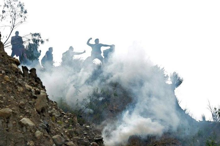 Bolivian coca growers from Los Yungas region confront riot police agents within a tear gas cloud, during a protest against a bill that caps legal coca crops extensions in La Paz on February 21, 2017