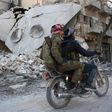 Rebels ride a motorcycle past a destroyed building in the northwestern Syrian border town of al-Bab on February 25, 2017