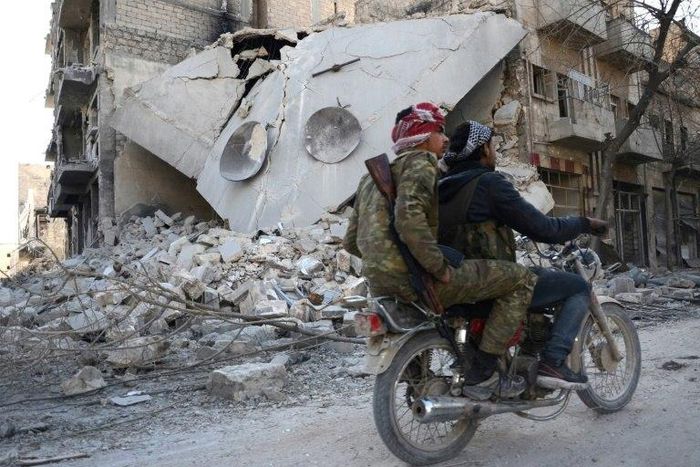 Rebels ride a motorcycle past a destroyed building in the northwestern Syrian border town of al-Bab on February 25, 2017