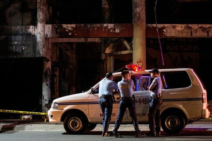 Policemen stand at a crime scene where the body of an alleged criminal lies on the street, in December 2016