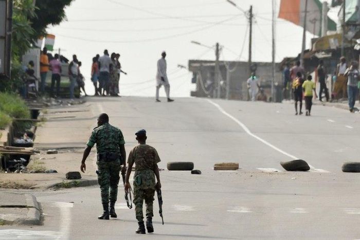 Soldiers patrol near tyres blocking the road in the Plateau business district of the Ivorian capital Abidjan on January 7, 2017 as angry troops took to the streets demanding salary hikes
