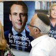 A French citizen walks past election posters of French presidential candidates Emmanuel Macron and Marine Le Pen before casting his vote at the French consulate in Tel Aviv on May 7, 2017