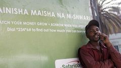 A man on phone next to an M-Shwari branded bus termini in Nairobi. The M-Shwari mobile banking service is set to be launched in Rwanda by April next year before rolling out to West Africa as it spreads its wings across Africa.