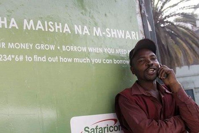 A man on phone next to an M-Shwari branded bus termini in Nairobi. The M-Shwari mobile banking service is set to be launched in Rwanda by April next year before rolling out to West Africa as it spreads its wings across Africa.