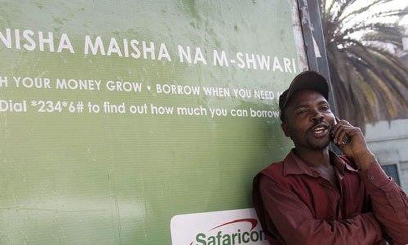 A man on phone next to an M-Shwari branded bus termini in Nairobi. The M-Shwari mobile banking service is set to be launched in Rwanda by April next year before rolling out to West Africa as it spreads its wings across Africa.