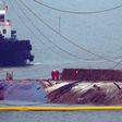 Workers check the hull of the Sewol ferry between two the barges that hauled it to the surface, nearly three years after it sank with the loss over 304 lives