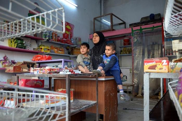 Umm Mustapha, a 27-year-old widow, with her sons in her grocery shop in Iraq's northern city of Mosul on November 28, 2018