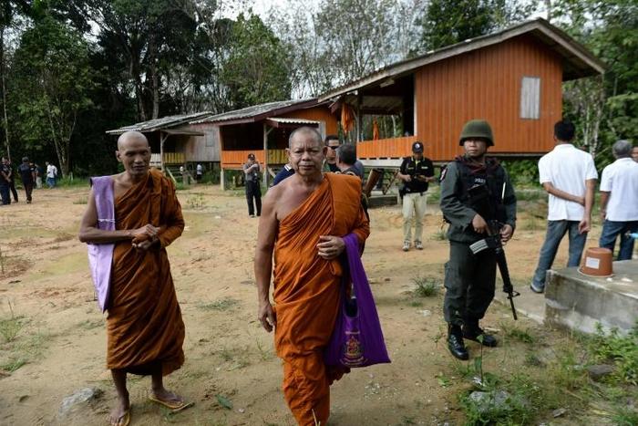 Buddhist monks and armed Thai police at the compound of the Rattanaupap temple, which was attacked by gunmen