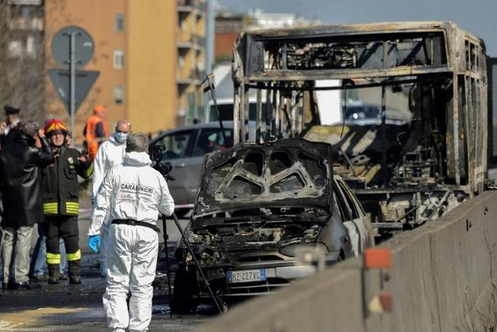 Forensic policemen and firefighters work near the wreckage of a school bus after rescuing some 50 children as the driver torched the vehicle, southeast of Milan.