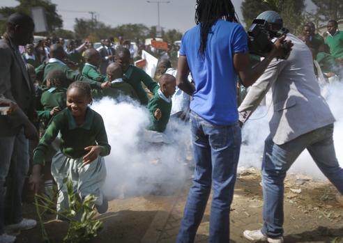 School children flee as a tear gas canister is fired by police in front of the school playground during a protest against alleged land grabbing at Langata Road Primary School in Nairobi.