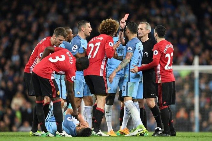 Referee Martin Atkinson (2R) shows the red card to send Manchester United's midfielder Marouane Fellaini (C) off after an altercation with Manchester City's striker Sergio Aguero (3L floor) during the Premier League football match April 27, 2017