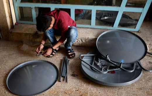 A young Iraqi prepares satellite dishes for sale at a market in east Mosul on April 15, 2017. Since Iraqi forces recaptured the sector from the Islamic State group in January, business has surged