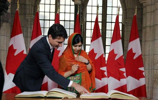 Canadian Prime Minister Justin Trudeau showed Nobel Peace laureate Malala Yousafzai where to sign in a guest book on Parliament Hill before she received an honorary Canadian citizenship