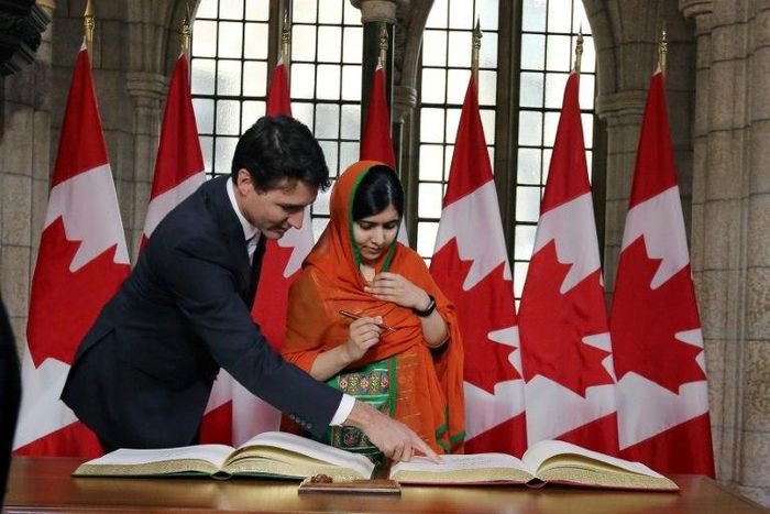 Canadian Prime Minister Justin Trudeau showed Nobel Peace laureate Malala Yousafzai where to sign in a guest book on Parliament Hill before she received an honorary Canadian citizenship
