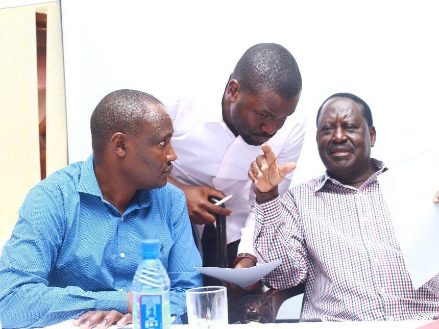 The late Raila Odinga speaking with Edwin Sifuna. John Mbadi looks on