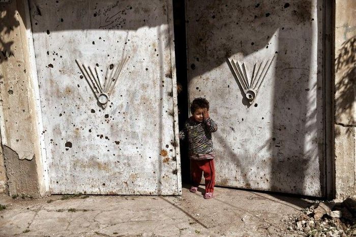 An Iraqi child stands outside a door in west Mosul, northern Iraq, on March 7, 2017, as Iraqi forces battle Islamic State (IS) group fighters to further advance inside the city