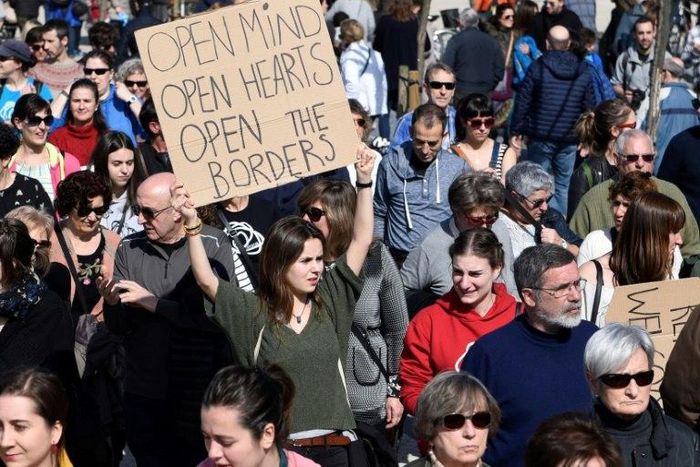 People hold placards during a pro-refugee demonstration in the Spanish Basque city of San Sebastian on February 26, 2017 as Spain has resettled only 1,100 of the 16,200 refugees it pledged to take in within two years