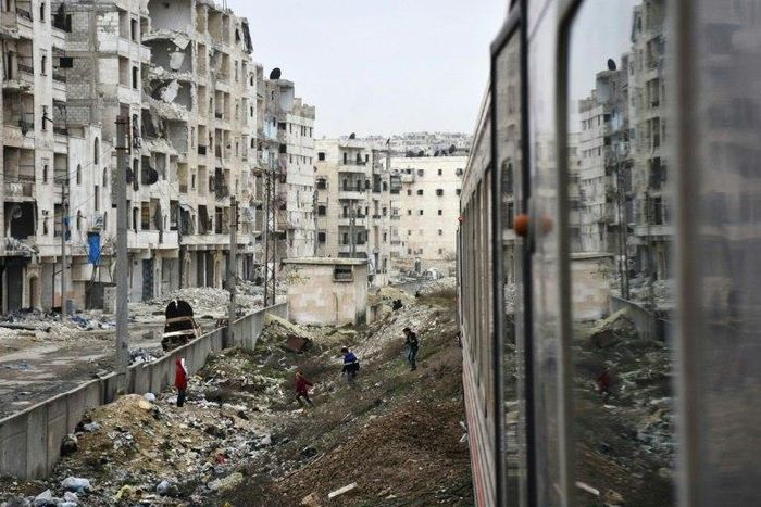 Syrian children look at a train travelling through Aleppo's devastated eastern districts for the first time in more than four years