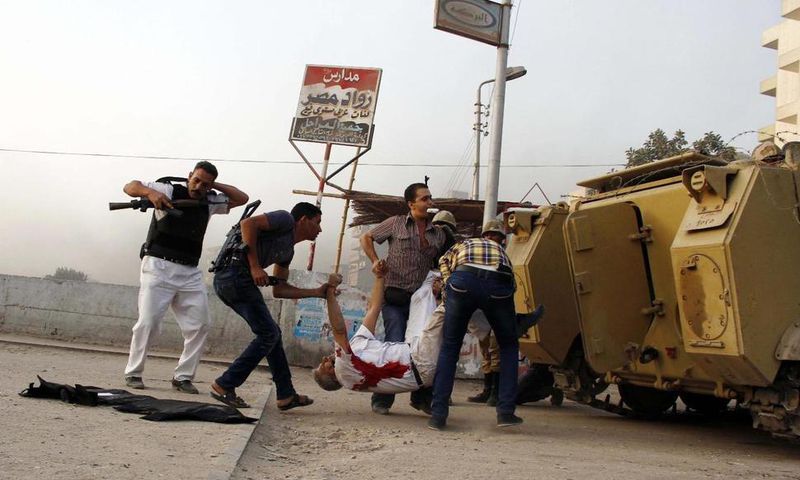 Egyptian security forces carry the lifeless body of Giza Police Gen. Nabil Farrag, center, who was killed after unidentified militants opened fire on security forces in the town of Kerdasa, Egypt.