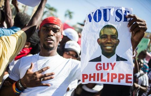 A supporter of Guy Philippe holds a sign during protests in front of the US embassy in Tabarre, Haiti in January 2017