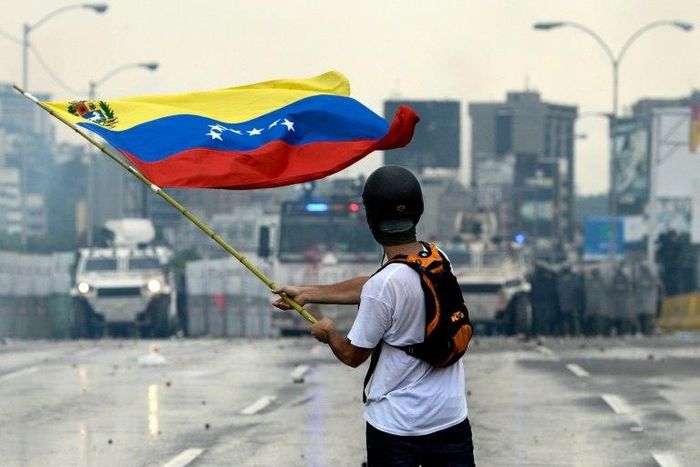 A Venezuelan opposition demonstrator waves a national flag in front of the riot police during a protest against President Nicolas Maduro, in Caracas, on May 8, 2017