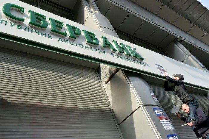 Activists of Ukraine's National Corps party stick placards on the shuttered entrance of a Russian Sberbank branch during a protest in Kiev on March 10, 2017
