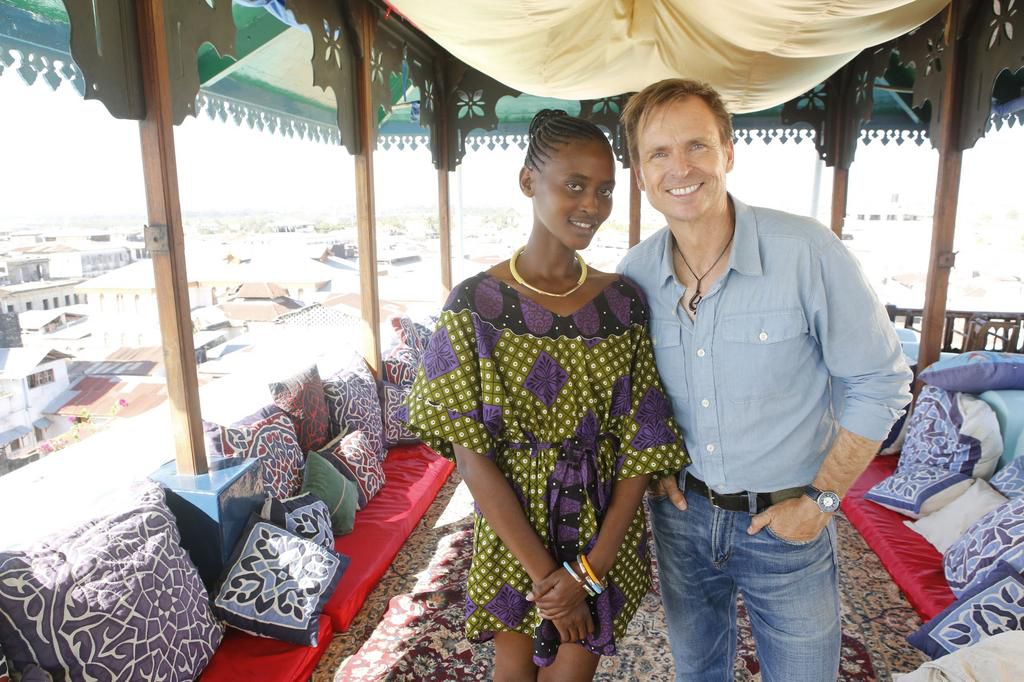 Host Phil Keoghan waits with a greeter at a Pit Stop in Tanzania.