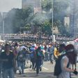 Demonstrators against Nicolas Maduro's government are seen amid a tear gas cloud during clashes with riot police in Caracas on April 8, 2017