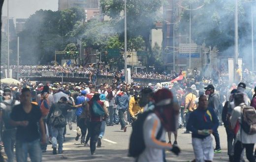 Demonstrators against Nicolas Maduro's government are seen amid a tear gas cloud during clashes with riot police in Caracas on April 8, 2017
