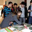 Claudia Martinez, a humanitarian worker at Burj al-Shamali refugee camp, looks at aerial shots taken by Palestinian refugees Mustafa Dakhlool (R) and Firas Ismail (L)