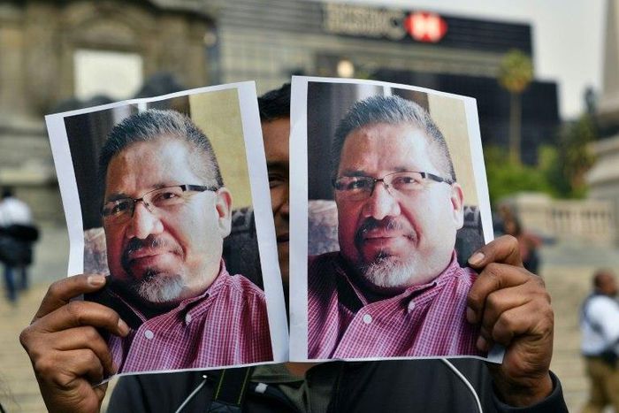 A photojournalist shows pictures of Mexican journalist Javier Valdez, murdered a day earlier, during a protest in Mexico City on May 16, 2017