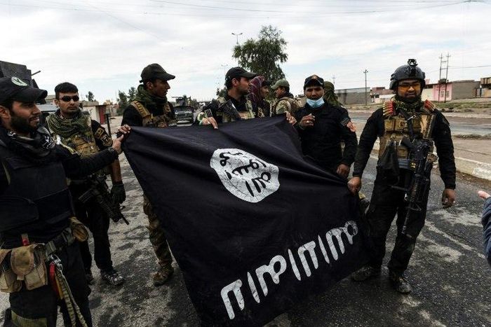 Iraqi soldiers pose with an Islamic State flag near Mosul on November 2, 2016