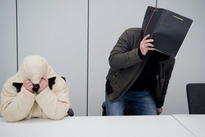 Defendants hide their faces at a regional court in Hildesheim, central Germany, on February 8, 2017