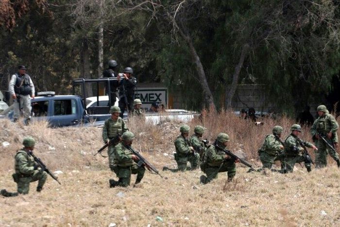 Soldiers take positions in front of villagers mounting roadblocks with burning tires to protest an army crackdown the day after a clash between soldiers and alleged fuel thieves on May 4, 2017