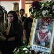 Jiranuch Trirat (L) is comforted by friends as she looks at a photograph of her 11-month-old daughter Natalie during funeral rites at a temple in Phuket, Thailand